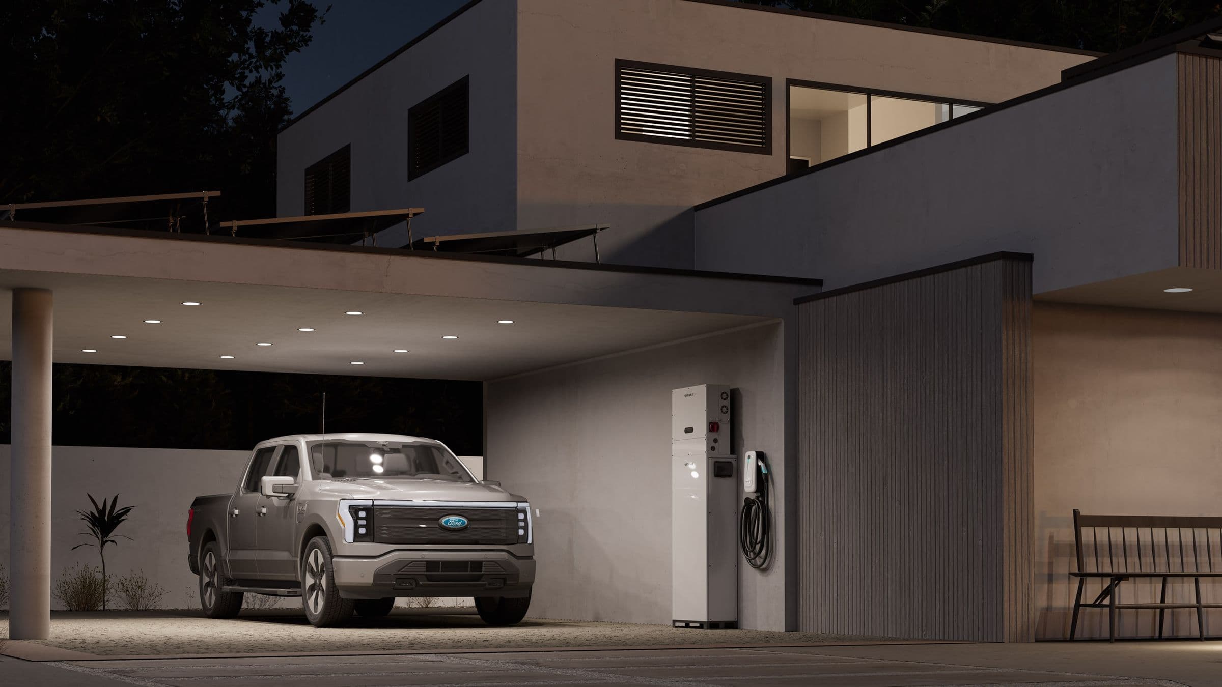 A modern home at dusk with the garage open, a Savant Power Storage 20 on the wall and an electric truck charging
